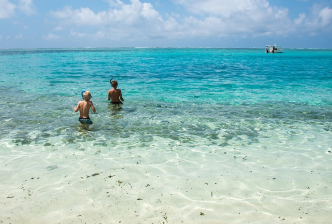 Two boys wade into still waters in Vanuatu to go snorkelling