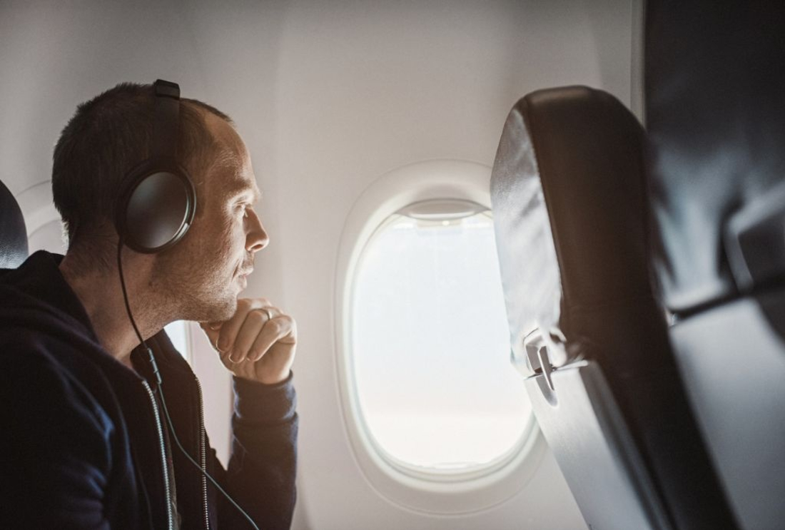 Image of person on a plane wearing noise cancelling headphones