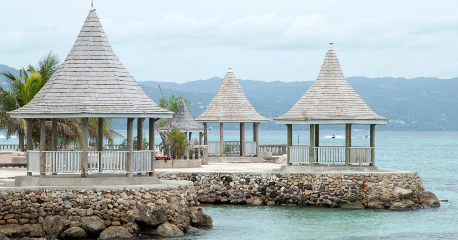 SeaGarden Beach Resort in Jamaica - several light grey gazebos on the waters edge