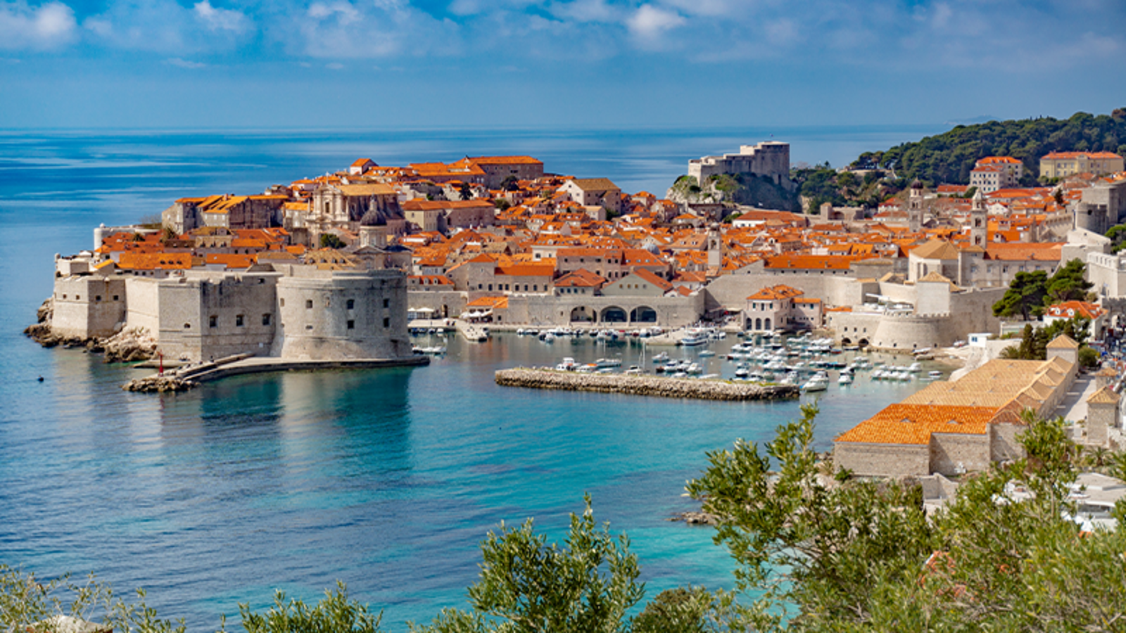 Dubrovnik city - baroque buildings and city walls along a shimmering blue coastline