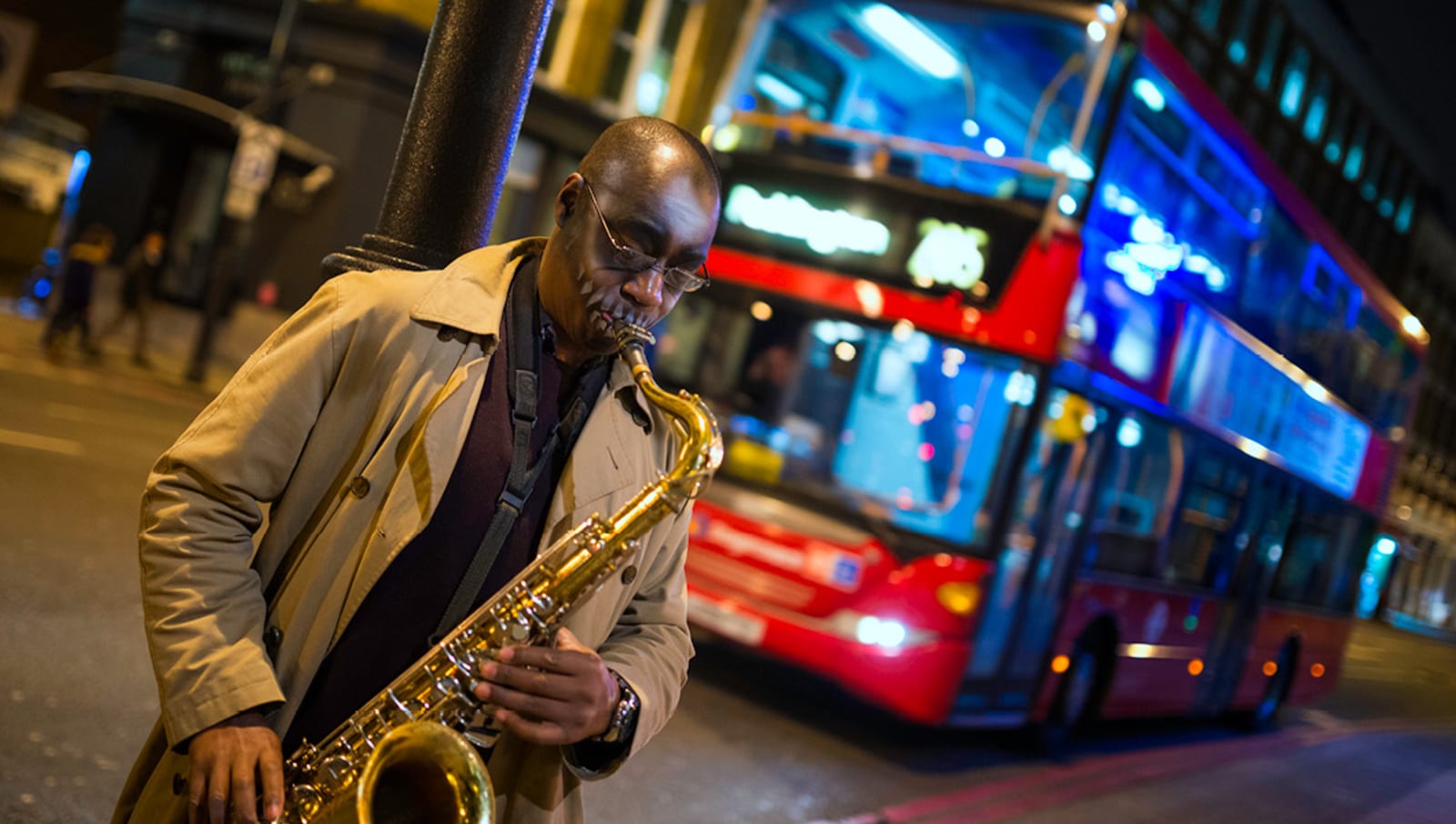 Man playing saxophone on England street at night