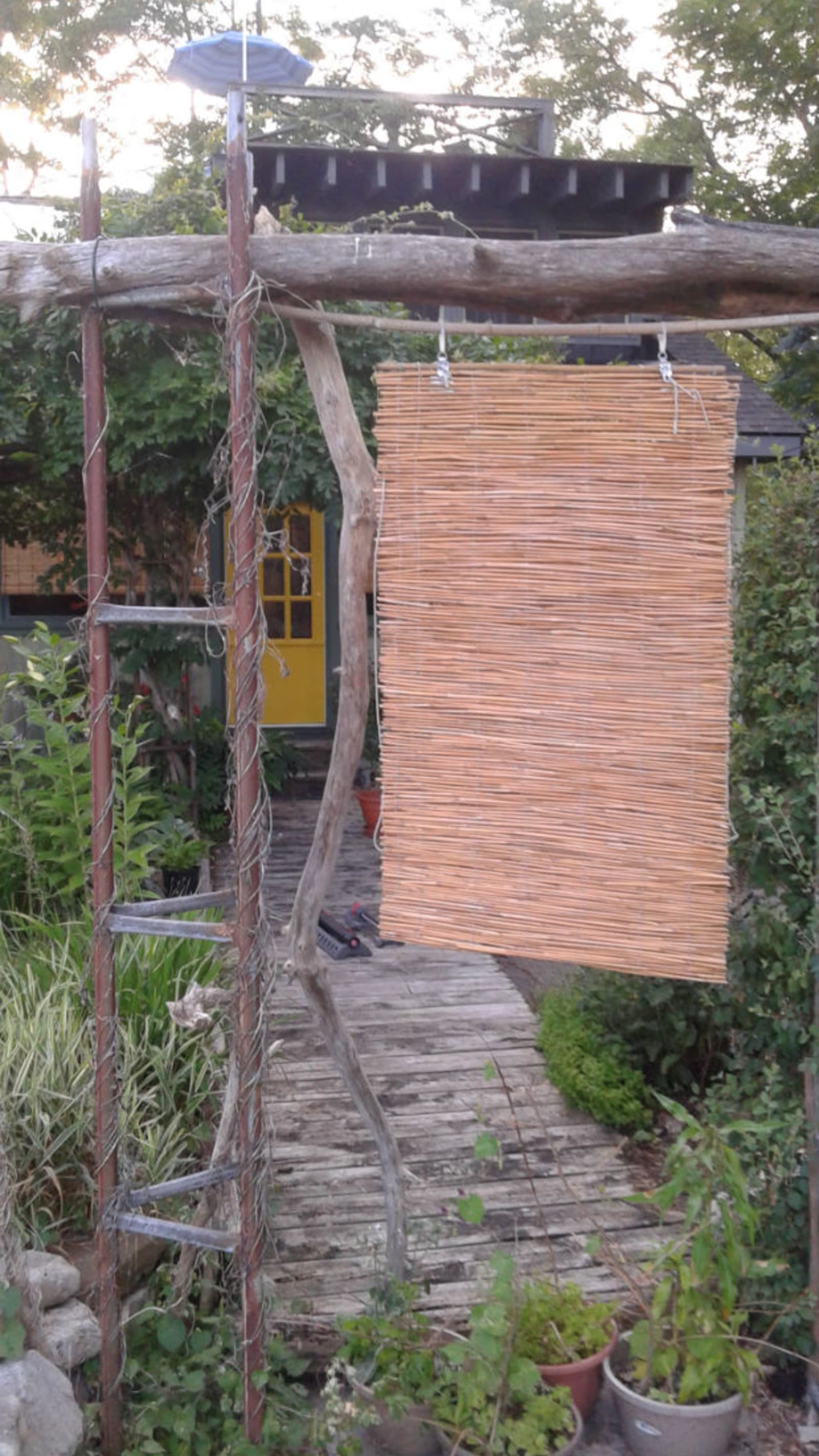 Wards Island House - wooden curtain hanging in the front yard, with a yellow door in the background