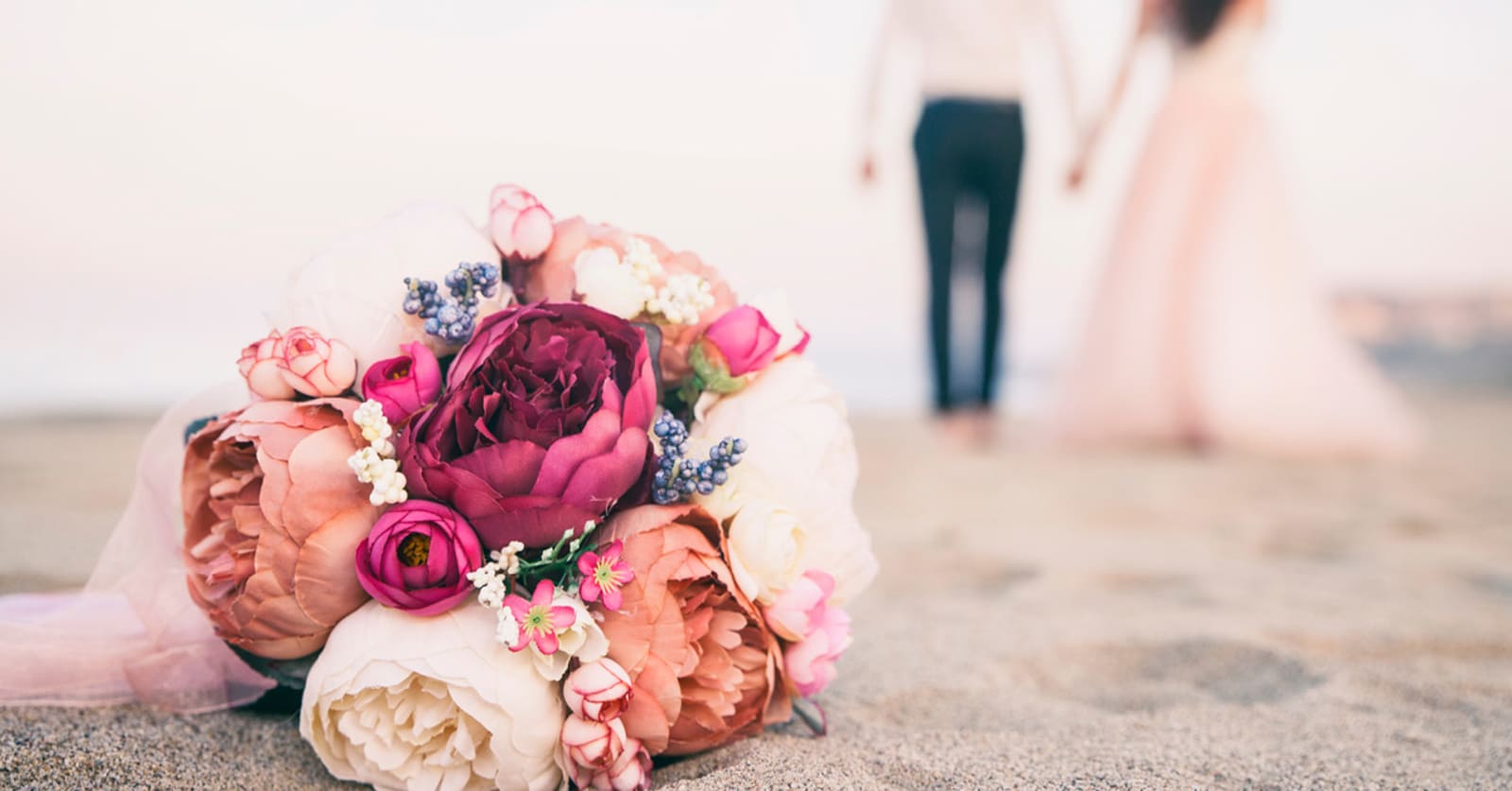 Closeup of a wedding bouquet on the beach with a couple standing out of shot