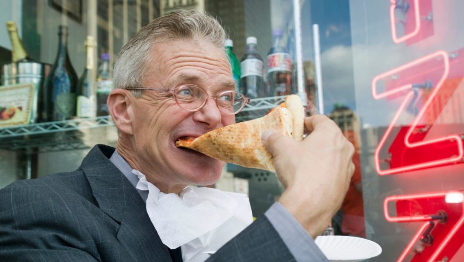 mature aged masc presenting person eats large piece of pizza 