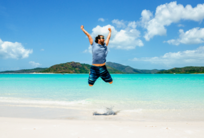 A man jumps for joy on Whitehaven Beach, Whitsunday Island