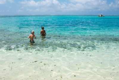 Two boys wade into still waters in Vanuatu to go snorkelling
