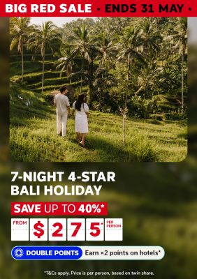 Couple holding hands walking through lush green Bali rice terraces for a Big Red Sale 7-night 4-star holiday saving up to 40% from $275 per person