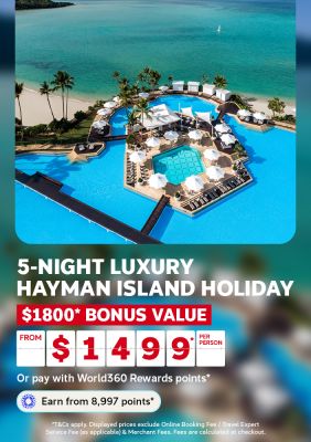 Aerial view of a beach resort pool surrounded by palm trees and turquoise ocean for a 5 night luxury Hayman Island holiday from 1499 per person