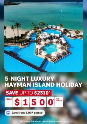 Hayman Island resort pool with white umbrellas beside turquoise Whitsundays waters for a 5-night luxury holiday saving up to $2310 from $1500 per person
