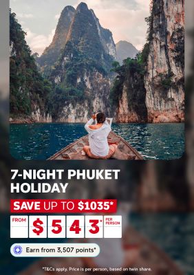 Person on the bow of a longtail boat gazing at towering limestone karsts for a 7-night Phuket holiday saving up to $1035 from $543 per person