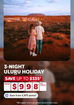 Couple gazing at Uluru glowing at dusk from red desert sands amid twinkling lights for a 3-night Uluru holiday saving up to $335 from $998 per person