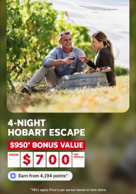 Couple sharing wine and a cheese platter in a sunny vineyard for a 4-night Hobart escape with $950 bonus value from $700 per person