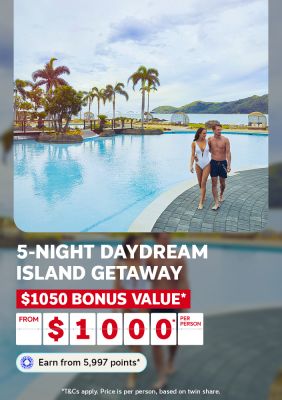 Couple walking beside a tropical resort pool at Daydream Island for a 5-night getaway with $1050 bonus value from $1000 per person