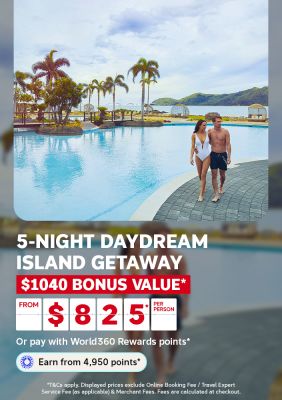 Couple walking beside a palm fringed lagoon pool for a 5-night Daydream Island getaway offering 1040 bonus value from 825 per person