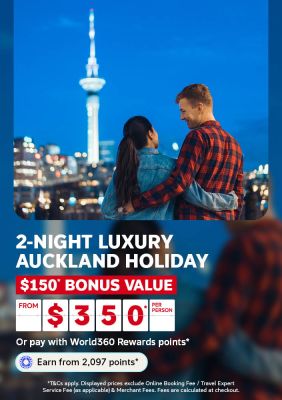 Couple admiring the Sky Tower and Auckland skyline at night for a 2 night luxury Auckland holiday with 150 bonus value from 350 per person