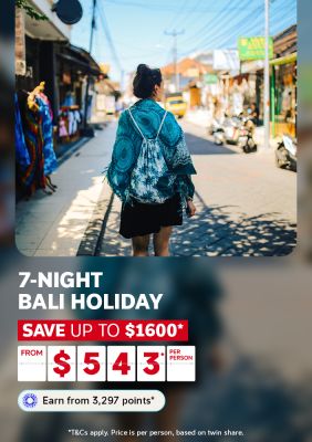 Woman strolling a sunny Bali street lined with colourful shops for a 7-night Bali holiday saving up to $1600 from $543 per person