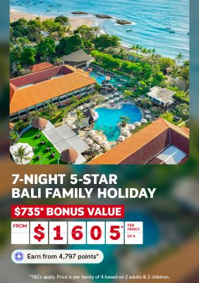 Aerial view of a resort pool water slide and gardens beside a Bali beach for a 7-night family holiday with $735 bonus value from $1605 per family of 4