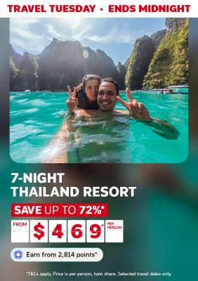 Couple making peace signs in turquoise water below limestone cliffs for a Travel Tuesday 7-night Thailand resort saving up to 72% from 469 per person