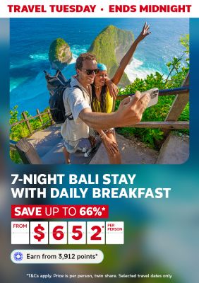 Couple taking a selfie on a steep walkway next to the ocean featuring a 7-night Bali stay with breakfast from $652
