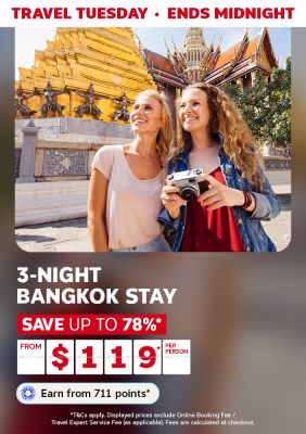 Women smiling, holding a camera next to the temple in Thailand featuring a 3-night Bangkok stay from $119
