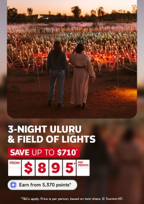 Two women admiring the illuminated Field of Light installation at dusk near Uluru for a 3-night stay saving up to $710 from $895 per person