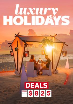 Couple having a candle-lit dinner on a beach at sunset featuring luxury holiday deals from $825*