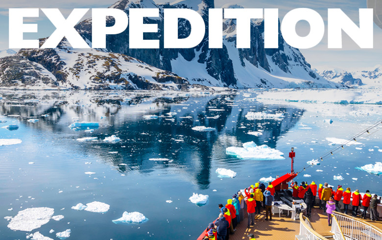 Expedition. People crowded at the front of a cruise ship looking out at ice flows and mountains in Antarctica