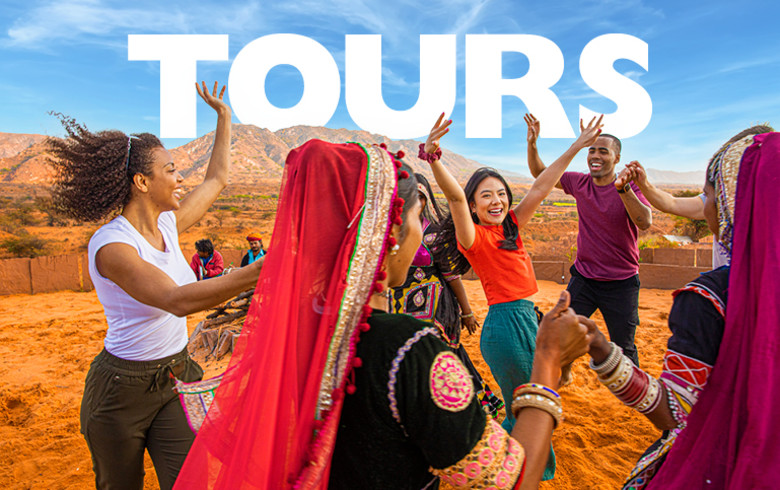 Tours - group of tourists dancing in a circle on red sand