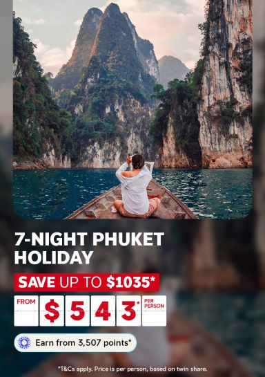 Person on the bow of a longtail boat gazing at towering limestone karsts for a 7-night Phuket holiday saving up to $1035 from $543 per person