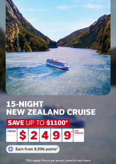 A travel promotional banner featuring an aerial view of a large cruise ship sailing through a dramatic fjord with steep, bush-covered mountains rising on either side under a blue sky, likely Milford Sound in New Zealand. Text reads: "15-Night New Zealand Cruise – Save up to $1,100* – From $2,499* per person. Earn from 9,996 points*." Fine print states: "T&Cs apply. Price is per person, based on twin share."