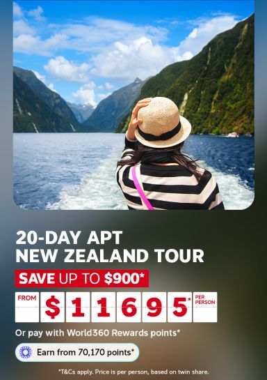 Woman holding her hat while gazing over a fjord for a 20-day APT New Zealand tour saving up to $900 from $1695 per person