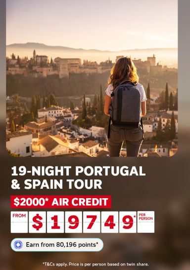 Backpacker overlooking the sunlit Alhambra and Granada rooftops for a 19-night Portugal and Spain tour with $2000 air credit from $1949 per person