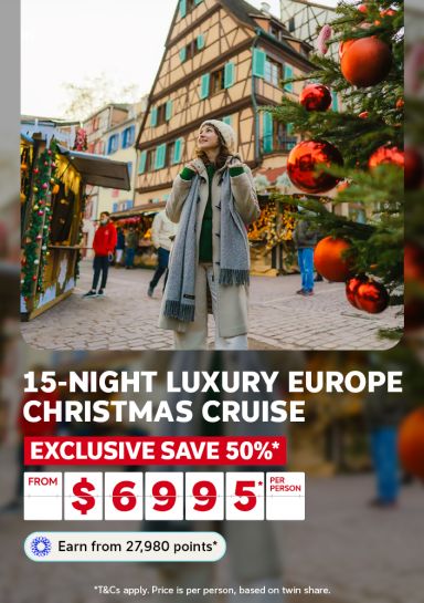 Woman gazing up at a festive European Christmas market beside a half-timbered building for a 15-night luxury Europe Christmas cruise saving 50% from $6995 per person
