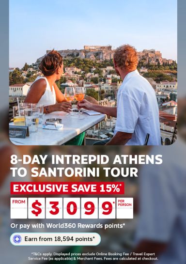 Couple toasting wine with the Acropolis behind them for an 8-day Intrepid Athens to Santorini tour saving an exclusive 15% from 3099 per person