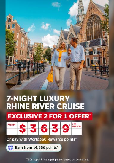 Couple strolling past historic Amsterdam architecture for a 7-night luxury Rhine River cruise with exclusive 2 for 1 offer from $3639 per person