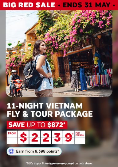 Traveller with a backpack exploring a flower-lined Hoi An street for an 11-night Vietnam fly and tour package saving up to $872 from $2239 per person