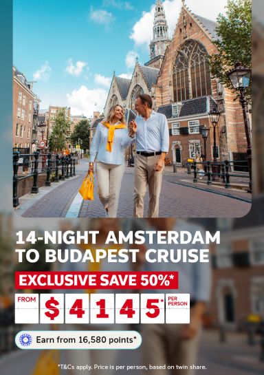 Couple strolling along an Amsterdam canal street beside a historic Gothic church for a 14-night Amsterdam to Budapest cruise saving 50% from $4145 per person