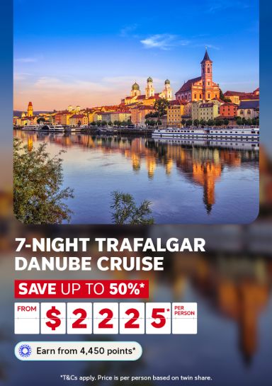 Baroque churches and golden spires of Passau reflected in the Danube at dusk for a 7-night Trafalgar Danube Cruise saving up to 50% from $2225 per person