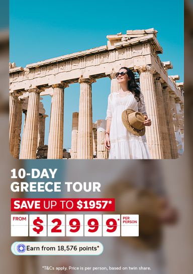 Woman smiling beside ancient Parthenon columns in Athens for a 10-day Greece tour saving up to $1957 from $2999 per person