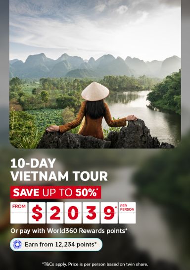Woman in conical hat overlooking limestone karst mountains and river for a 10-day Vietnam tour saving up to 50% from $239 per person