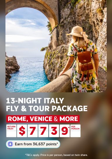 Woman in a sundress admiring the turquoise Amalfi coastline through a stone archway for a 13-night Italy fly and tour package from $7739 per person
