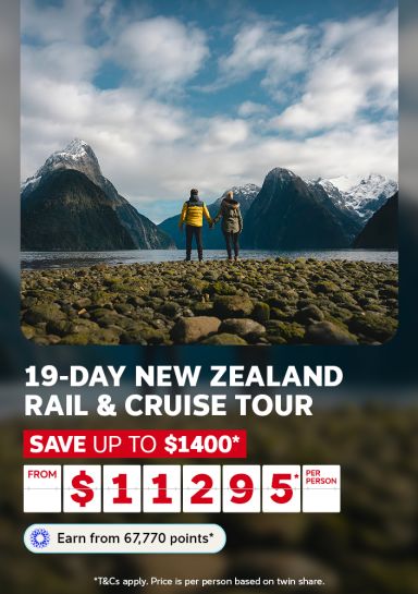 Couple gazing at snow capped mountains over Milford Sound for a 19 day New Zealand rail and cruise tour saving up to $1400 from $1129 per person