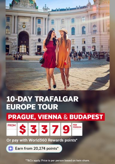 Friends laughing arm in arm before a grand European palace for a 10-day Trafalgar tour through Prague Vienna and Budapest from $3379 per person