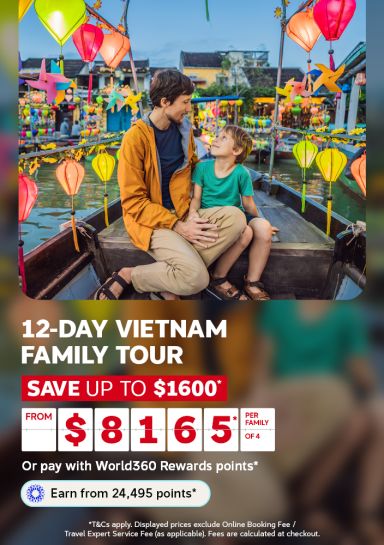 Father and child on a wooden boat through Hoi An’s colourful lantern-lit waters for a 12-day Vietnam family tour from $8165 saving up to $1600