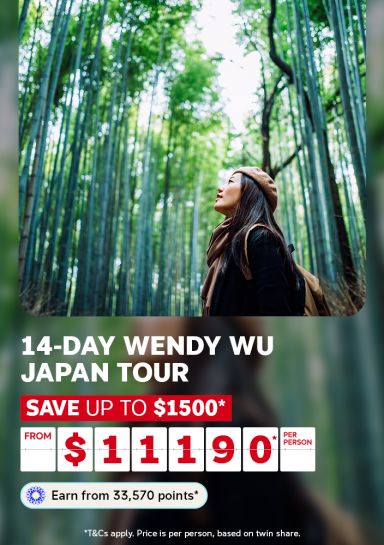Woman gazing up through a towering Arashiyama bamboo grove in Japan for a 14-day Wendy Wu Japan Tour saving up to $1500 from $11190 per person