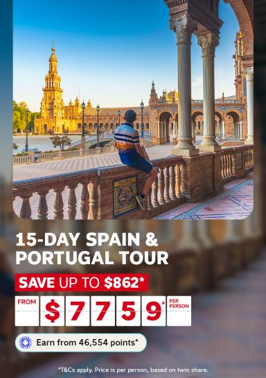 Man sitting on wall admiring golden Plaza de España for a 15 day Spain and Portugal tour saving up to $862 from $759 per person