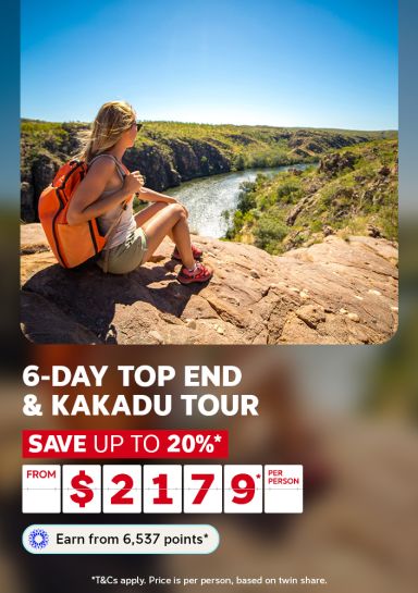Hiker with an orange backpack resting on a cliff above a Kakadu gorge for a 6-day Top End and Kakadu Tour saving up to 20% from $2179 per person
