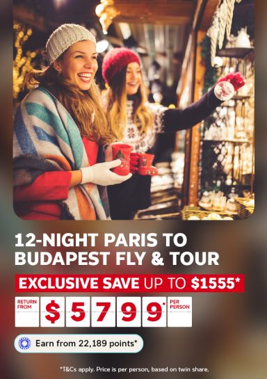 Two people laughing at a festive Christmas market for a 12-night Paris to Budapest fly and tour saving up to $1555 from $5799 per person
