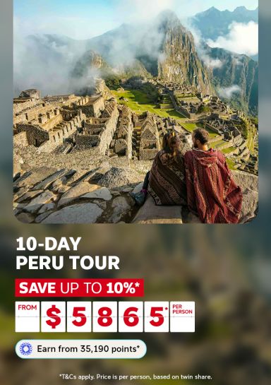 Couple wrapped in blankets overlooking the misty ruins of Machu Picchu for a 10-day Peru tour saving up to 10% from 5865 per person