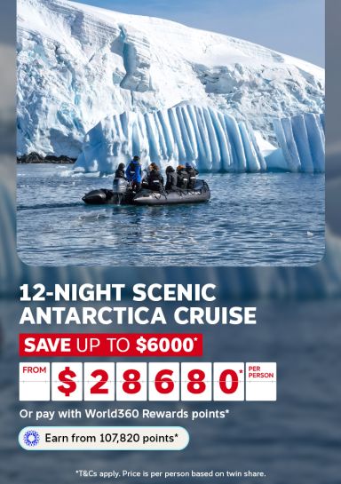 Small boat carrying passengers past towering blue glacier ice for a 12-night scenic Antarctica cruise saving up to $6000 from $2680 per person